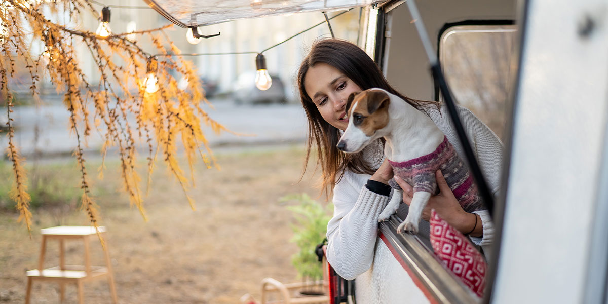 Woman and baby near an RV window surrounded by fall foliage